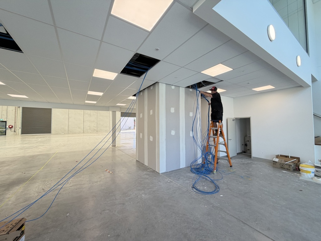 Technician on scissor lift installing WiFi access point in Melbourne warehouse