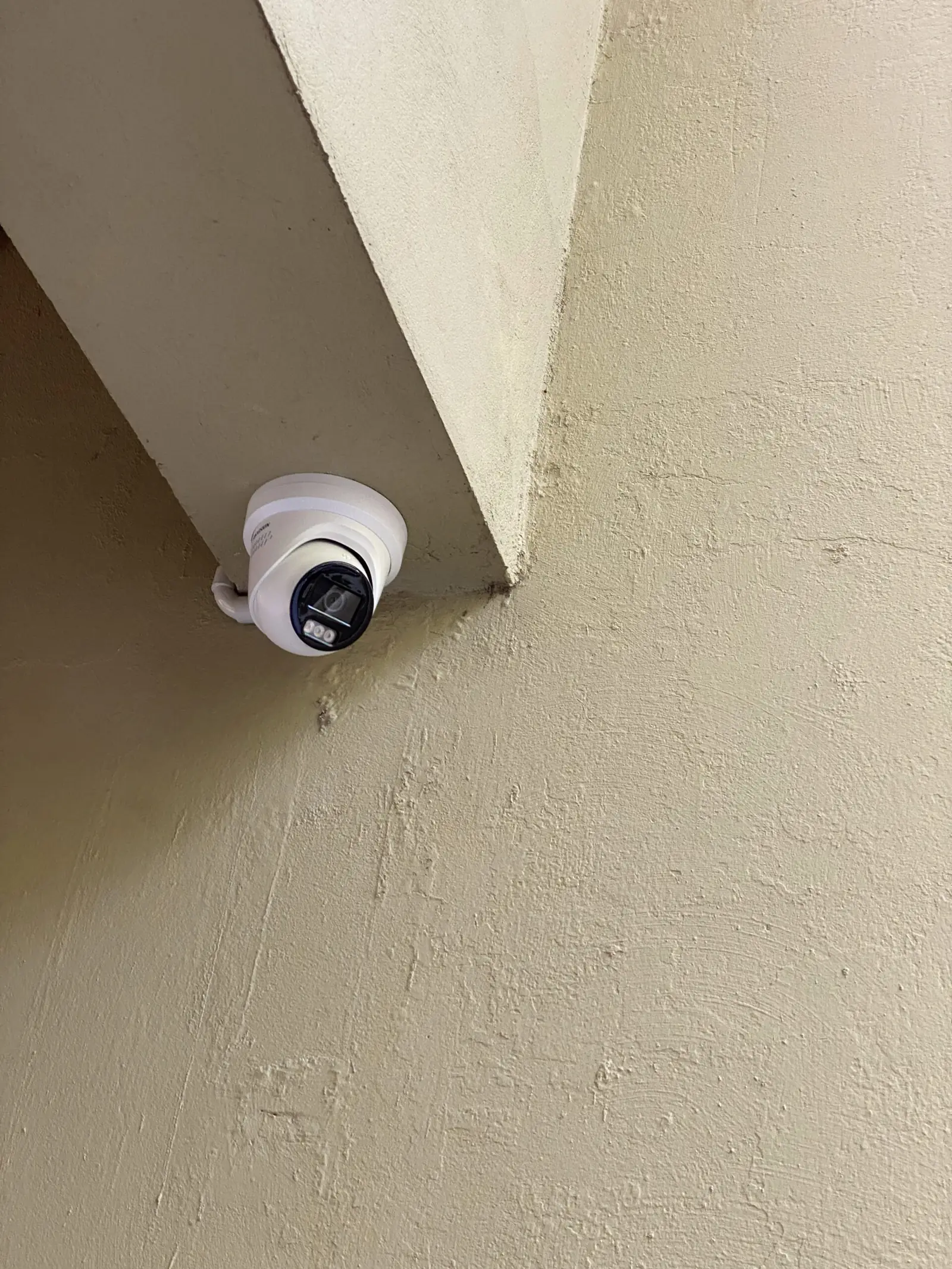 White dome camera mounted on a rendered wall beneath an archway