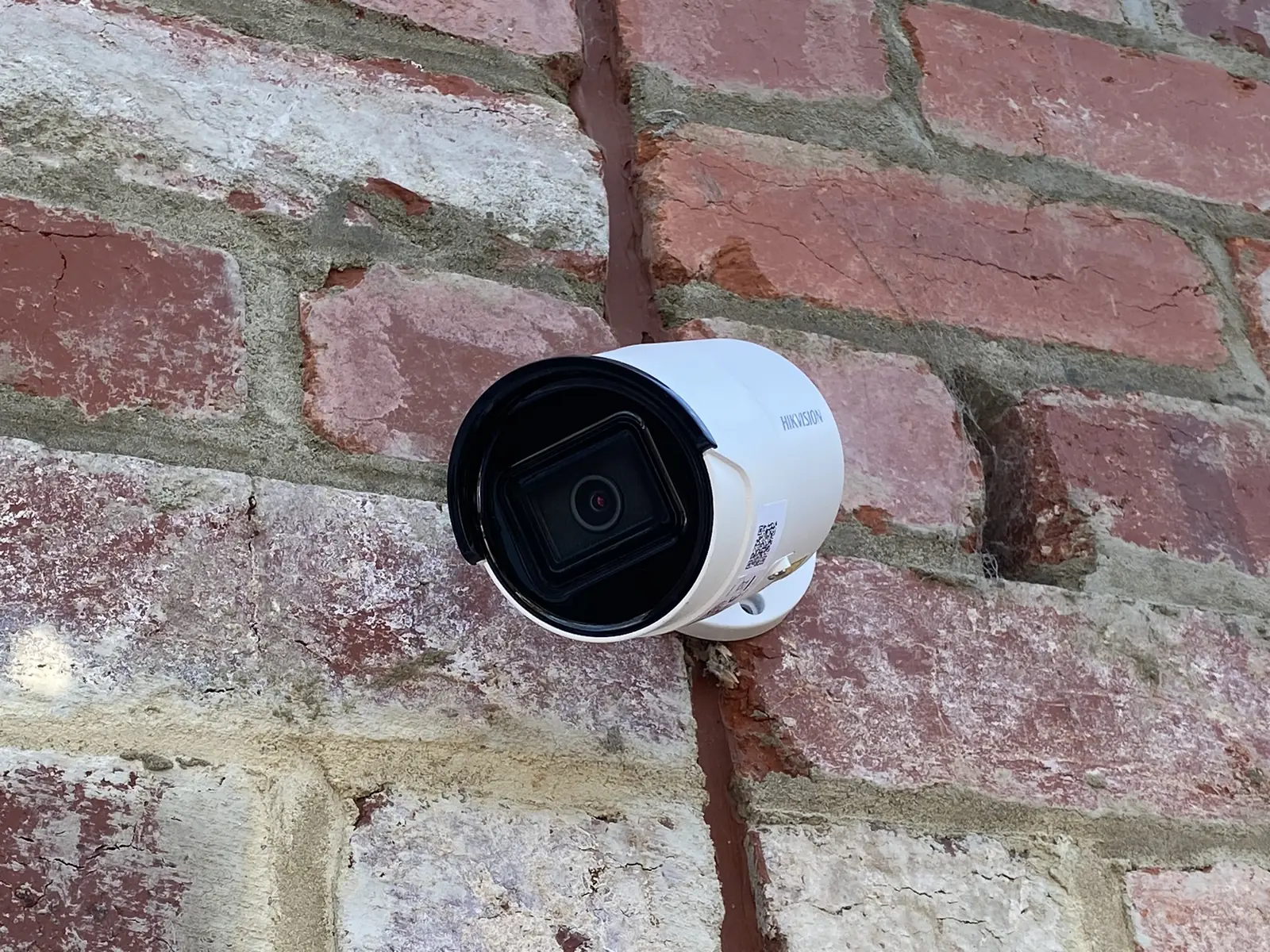 Bullet camera mounted on an exposed brick wall covering an entrance