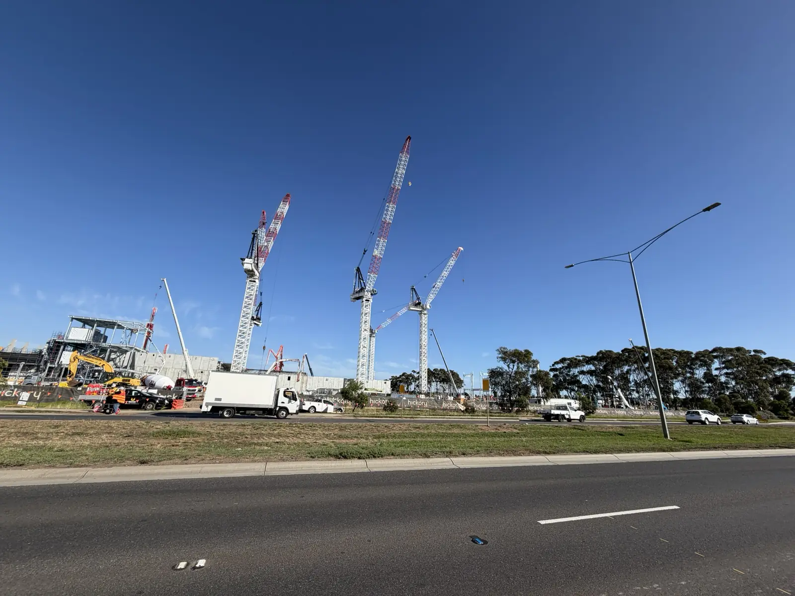 Construction site with tower cranes against a clear sky and trucks on the ground