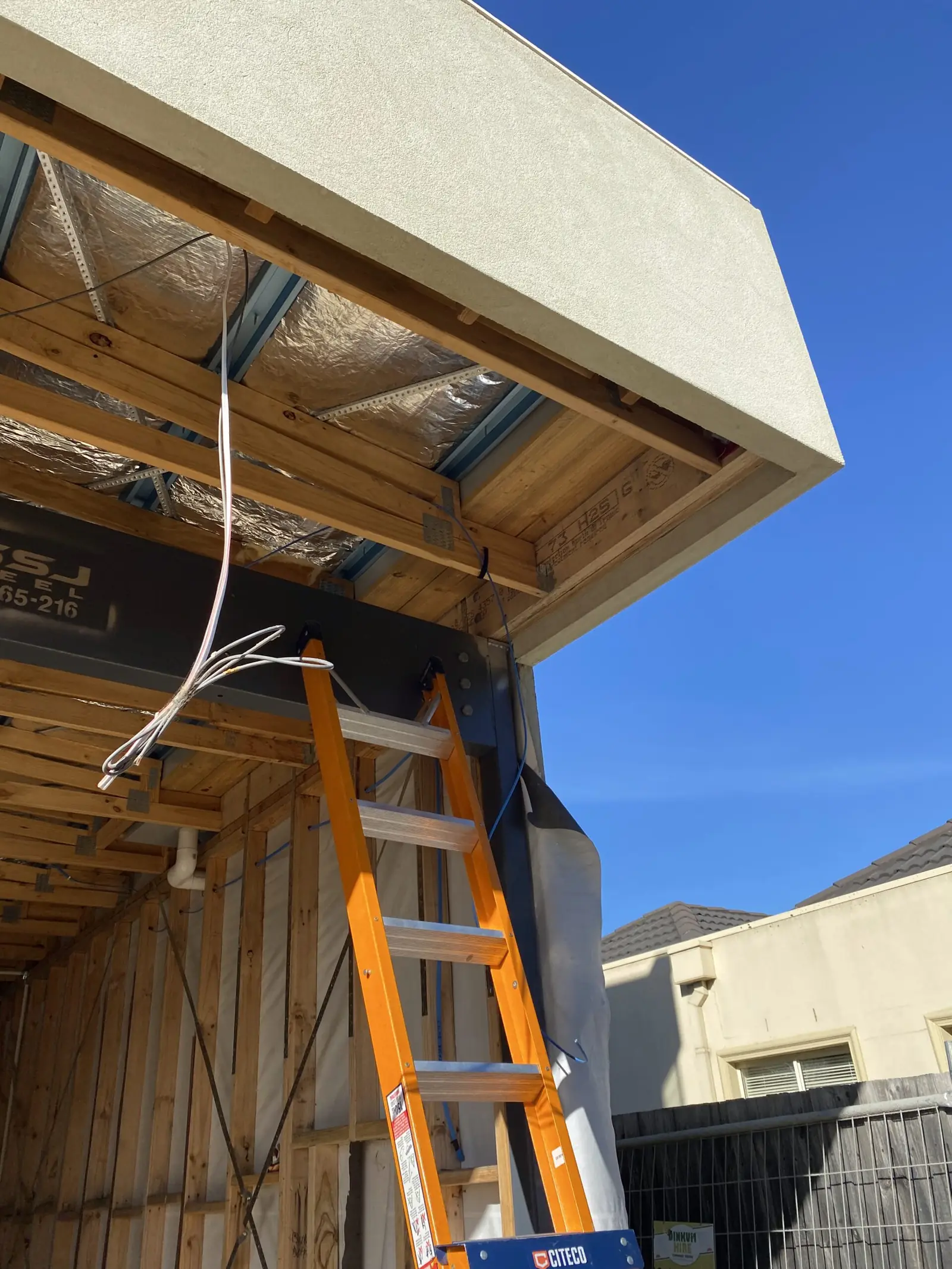 Timber-framed building under construction with a ladder against the exterior wall