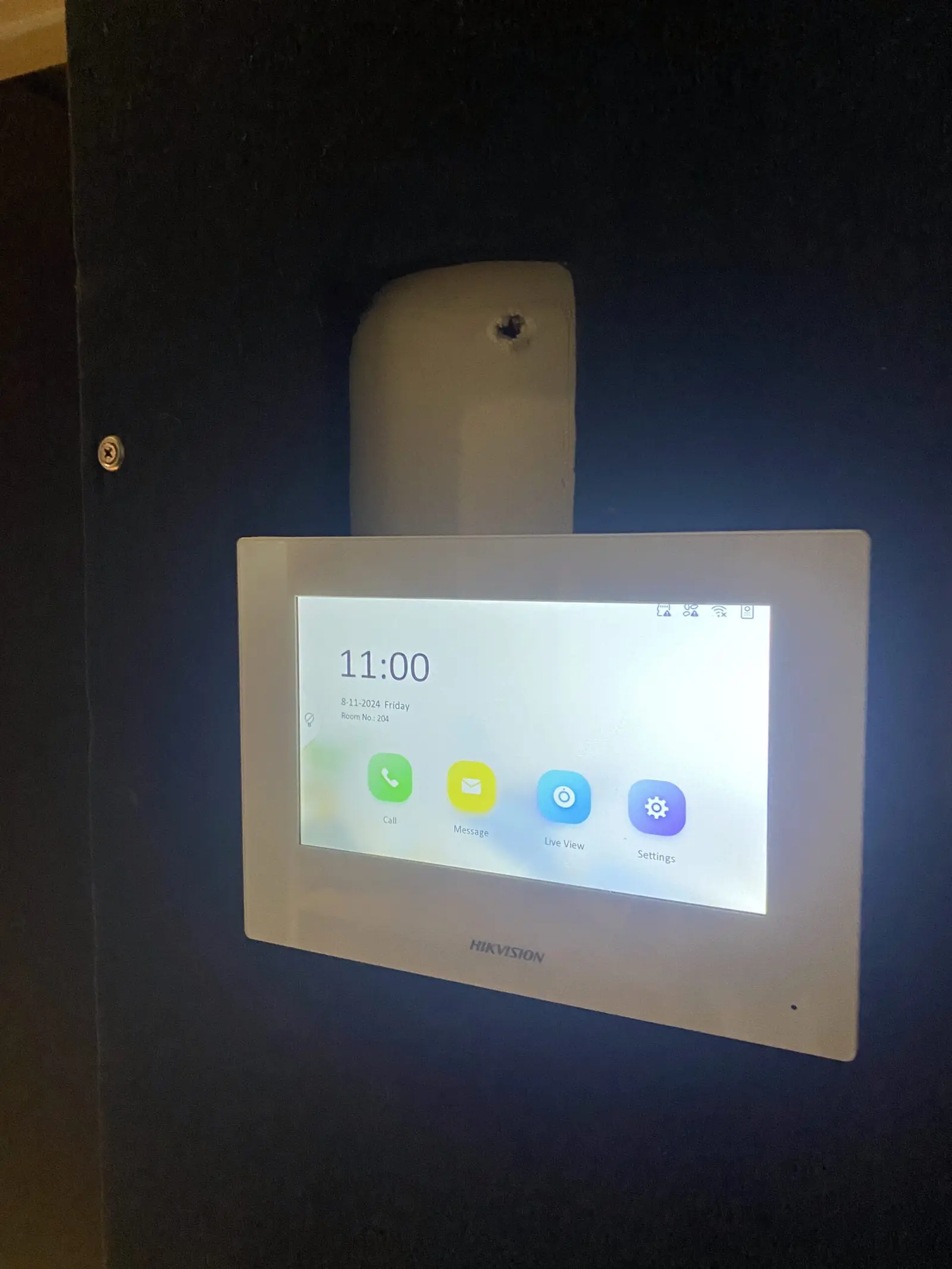 Wall-mounted intercom touchscreen showing the time and call, message and live view icons