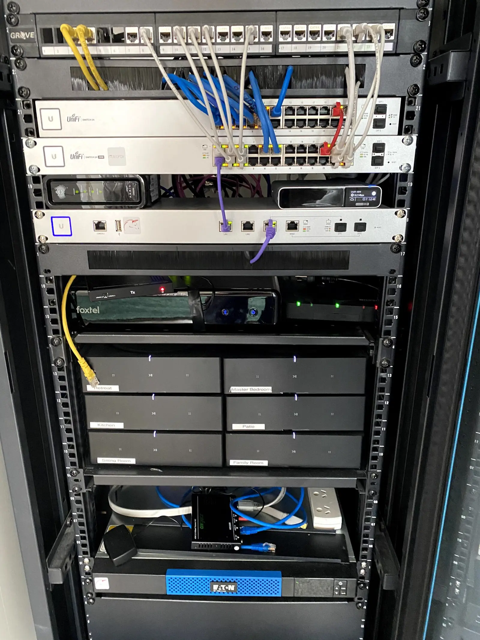 Home network rack with switches and patch panels labelled by room — kitchen, family room, patio