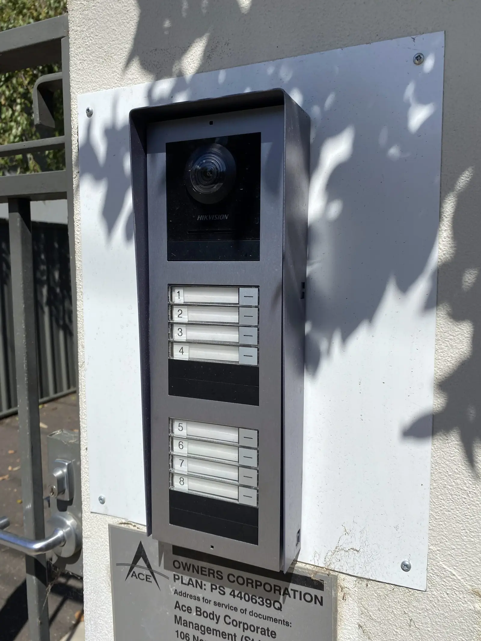 Outdoor intercom panel with a camera above numbered call buttons for eight units