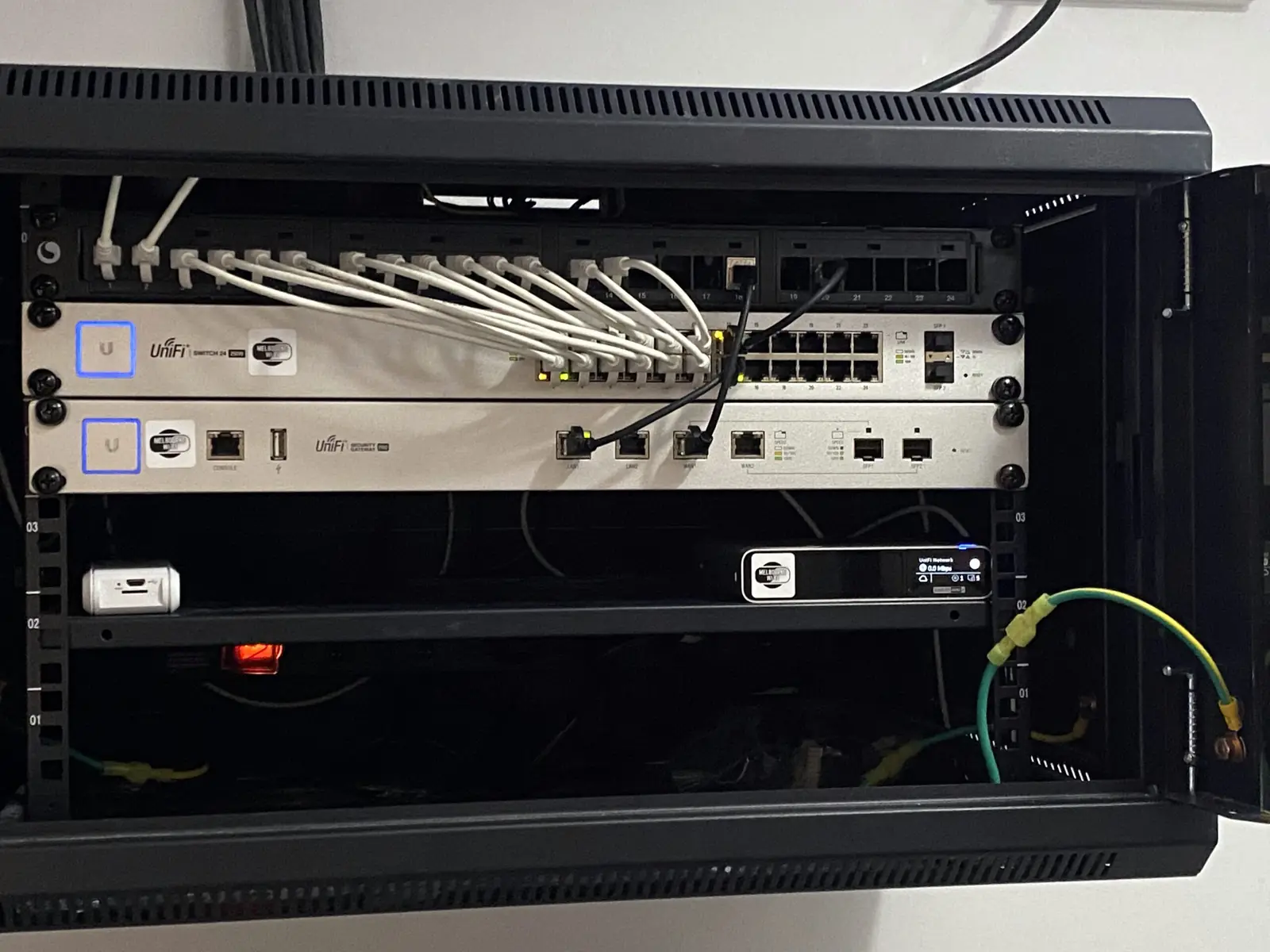 Two rack-mounted UniFi switches with patched Ethernet cables and lit port indicators