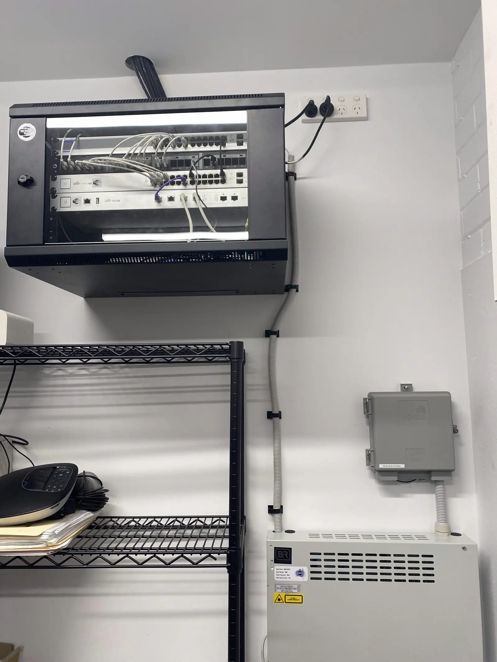 Open wall-mounted equipment rack with patch panels, switches and bundled cabling